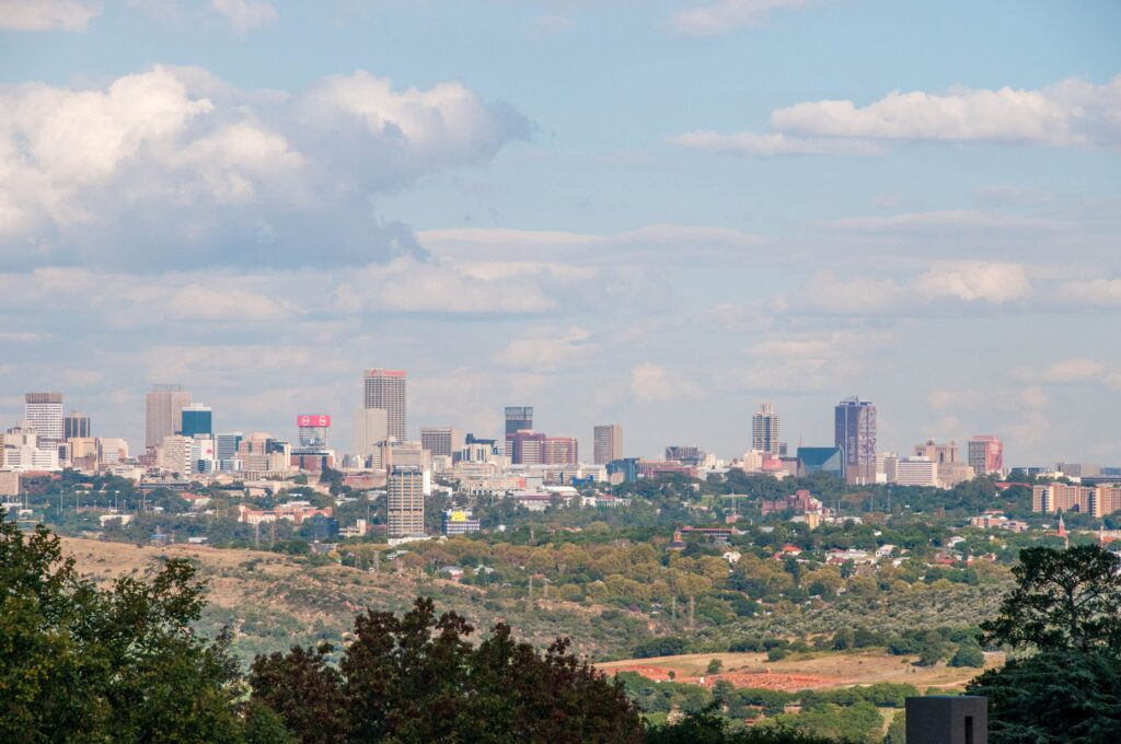 Stunning panoramic view of Johannesburg skyline with lush greenery and blue skies.